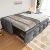 A gray sofa bed is shown in a room with wooden floors and a rug. The sofa bed is partially extended, revealing a metal frame underneath. There are blankets and a pillow on the sofa bed. Produktbild-Vorschau
