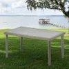 A rectangular table is placed on a grassy lawn next to a lake with a pier and a boathouse in the background. Anteprima dell’immagine prodotto