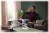 A man is talking on the phone while standing near an ironing board with a steam generator iron and its base station. Voir les images du produit