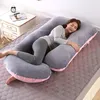 A woman is sleeping on a large U-shaped pregnancy pillow on a bed. Náhled obrázku produktu