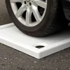 A car tire is resting on a white shower tray, which is placed on an asphalt surface. Produktbild-Vorschau