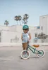 A child stands with a balance bike outdoors. Produktbild-Vorschau
