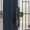 A close-up view of a dark gray gate handle and lock mechanism on a metal fence. Náhled obrázku produktu
