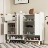 A white shoe cabinet with multiple shelves and doors, filled with various shoes. A brown handbag sits on top. Produktbild-Vorschau