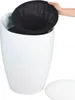 A hand is shown placing a black mesh liner into a white laundry hamper that has a lid next to it. Podgląd zdjęcia produktu