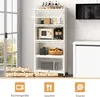 A white kitchen storage shelf with various items on its shelves, placed next to a window and a white cabinet. Produktbild-Vorschau