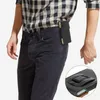 A person wearing a plaid shirt and dark pants, with a black phone pouch attached to their belt. Náhled obrázku produktu