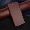A brown leather flip cover for a phone is displayed on a dark background with rolled leather materials. Produktbild-Vorschau