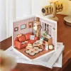 A miniature diorama of a living room scene, complete with furniture, decorations, and a small lamp. Podgląd zdjęcia produktu