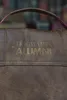 Close-up of a brown leather bag with gold lettering. Anteprima dell’immagine prodotto