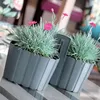 Two gray planters with pink flowers on a table. Produktbild-Vorschau