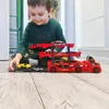 A young boy is playing with a toy car carrier truck and cars on a wooden floor. Náhled obrázku produktu