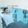 A man relaxing in an office chair with his feet up, while a fan blows cool air on him. Produktbild-Vorschau