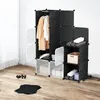 A modular wardrobe with clothes hanging and folded items inside, set up on a wooden floor against a white wall. Náhled obrázku produktu