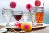 A collection of glasses filled with different beverages, decorated with colorful party accessories, set on a tray. Podgląd zdjęcia produktu