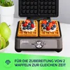 A waffle maker with two waffles topped with cream and berries, next to some fruit. Náhľad obrázku produktu