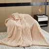 A plush blanket draped over a chair, with a nightstand and wall paneling in the background. Produktbild-Vorschau