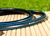 A coiled garden hose lies on a wooden surface with green grass in the background. Voir les images du produit