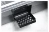 A close-up of a black perforated drip tray extended from a stainless steel appliance. Produktbild-Vorschau