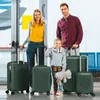 A family stands with their luggage in what appears to be an airport or train station. Anteprima dell’immagine prodotto
