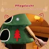 A hand is brushing a green cat tree shaped like a Christmas tree, with a sofa and lamp in the background. Anteprima dell’immagine prodotto