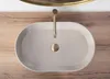 A top-down view of a beige matte washbasin with a gold faucet and drain. Produktbild-Vorschau