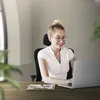 A woman is working on a laptop at a desk in an office. Produktbild-Vorschau