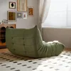 A green beanbag chair is placed on a patterned rug in a room with framed art on the wall and a window with blinds. Produktbild-Vorschau
