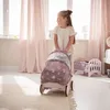 A young girl is pushing a doll stroller in a room with pink curtains and a doll bed. Náhled obrázku produktu