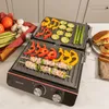 A close-up shot of an electric grill with food being cooked on it, including skewers of meat and vegetables, and sliced bell peppers and zucchini. Voir les images du produit