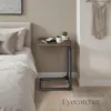 A bedside table next to a bed, with a mug and a plant on top. Náhled obrázku produktu