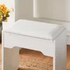 A close-up shot of a white vanity stool with a cushioned seat, placed on a woven rug. Voir les images du produit