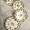 A set of plates and a cup with a floral pattern on a textured surface. Náhľad obrázku produktu