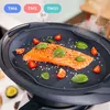 A close-up of a steaming piece of salmon being cooked on a dark gray silicone mat, surrounded by cherry tomatoes and basil leaves. The mat is placed on top of a kitchen appliance. Produktbild-Vorschau