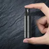 A hand holding a small, dark gray safety hammer with a seatbelt cutter. Náhled obrázku produktu