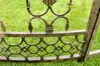 A close-up view of ornate metalwork, likely part of a garden structure, set against a backdrop of green grass. Anteprima dell’immagine prodotto