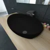 A black oval sink on a light wood countertop in a modern bathroom setting. Náhľad obrázku produktu