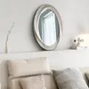 A mirror is displayed on a shelf above a sofa with pillows. Anteprima dell’immagine prodotto