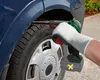 A person wearing a white glove is using a cordless band file on the fender of a blue car near the wheel. Produktbild-Vorschau