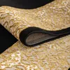 A close-up view of a rolled-up rug with a black border and a gold and white abstract pattern. Voir les images du produit