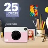 A pink and white Kodak instant print camera is displayed on a desk with art supplies and a small framed picture. Podgląd zdjęcia produktu