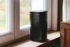 A black dehumidifier sits on a wooden windowsill next to a window. Produktbild-Vorschau