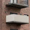 Two balconies on a brick building, one with a privacy screen. Produktbild-Vorschau