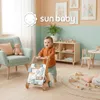 A baby is using a wooden walker in a nursery room. Produktbild-Vorschau