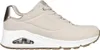 A side view of a single beige Skechers sneaker with a white sole and gold accents on a white background. Produktbild-Vorschau