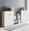 A modern office storage unit with white doors and oak Sonoma accents, set against a gray wall. Produktbild-Vorschau