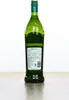A green glass bottle of Noilly Prat Original Dry Vermouth stands on a wooden surface against a white background. Produktbild-Vorschau
