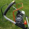 Close-up of the handle and control panel of a lawnmower, with grass in the background. Produktbild-Vorschau