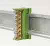 A close-up shot of a green terminal block mounted on a metal rail. Produktbild-Vorschau
