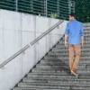 A man walks up a concrete staircase with a metal handrail. Náhled obrázku produktu